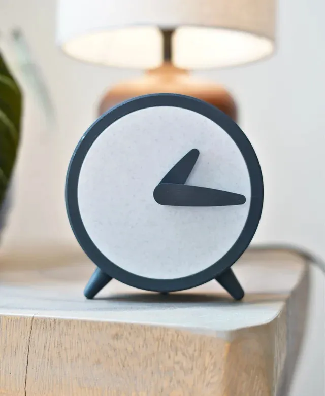 A minimal round wall clock on a limestone wall