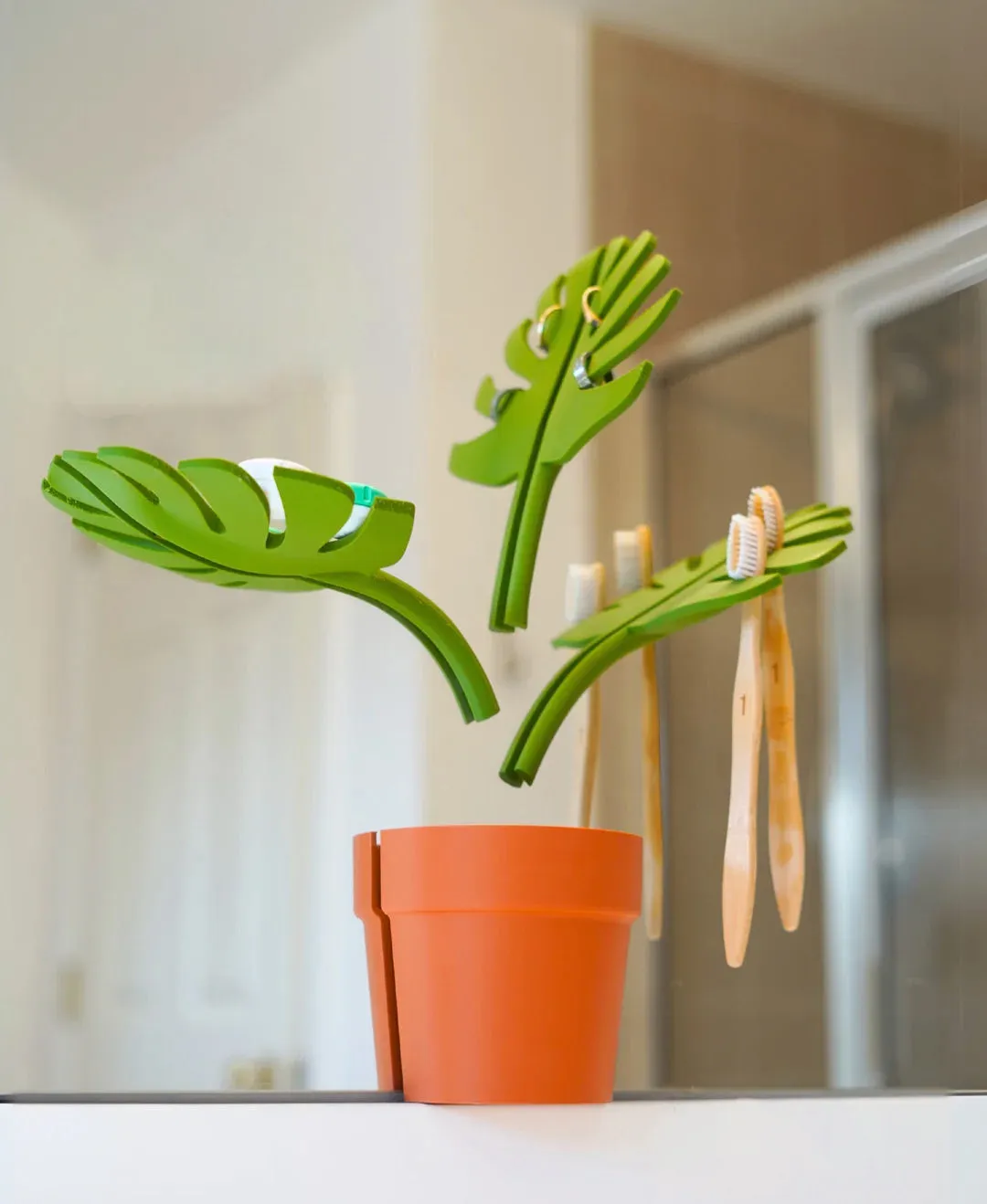 Monstera Bathroom Organiser, green leaf arms holding a terracotta pot on a mirror